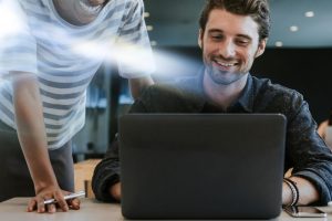 Homem sorrindo ao usar notebook com rede rápida após suporte técnico da Mais IT para resolver problemas de lentidão na infraestrutura de TI empresarial