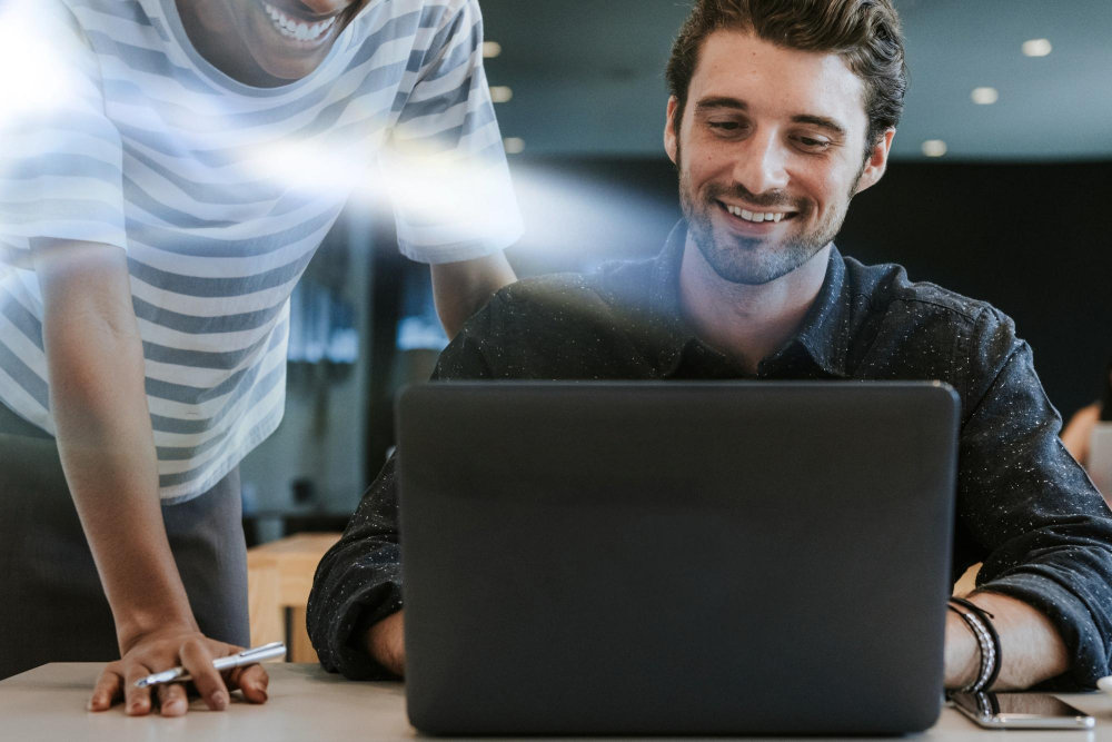 Homem sorrindo ao usar notebook com rede rápida após suporte técnico da Mais IT para resolver problemas de lentidão na infraestrutura de TI empresarial
