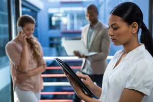 Profissionais usando celular, notebook e tablet em ambiente corporativo moderno